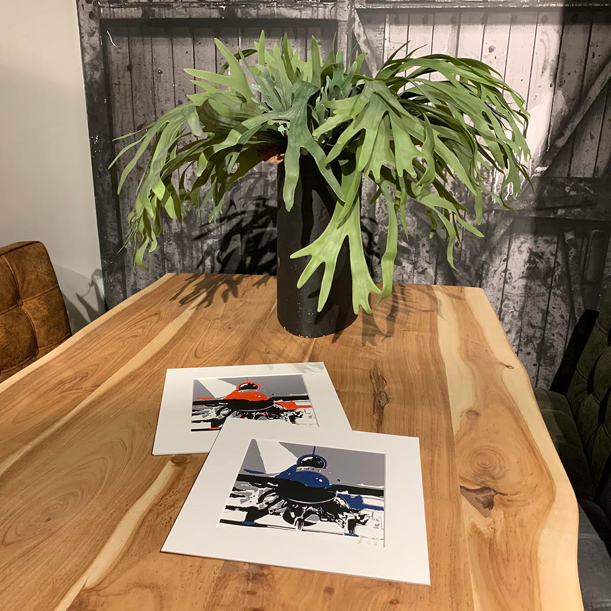 Three colour screen prints, red or blue, black and grey, of a Lockheed Martin F-16 on a dinner table.