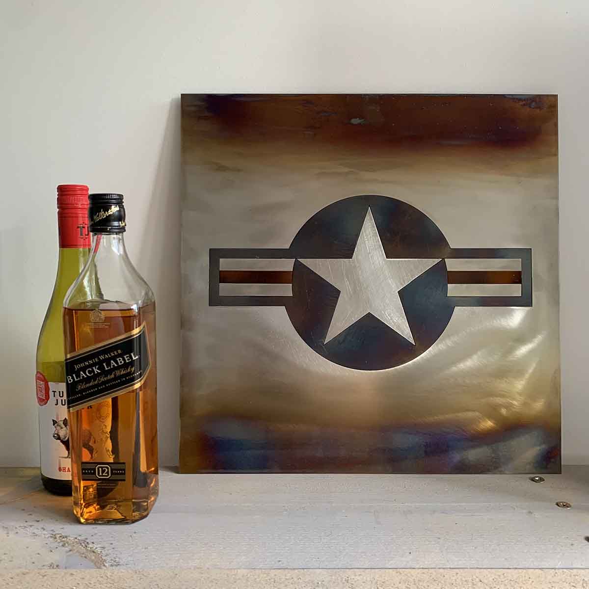 United States Air Force steel roundel artwork next to some bottles on a shelf.