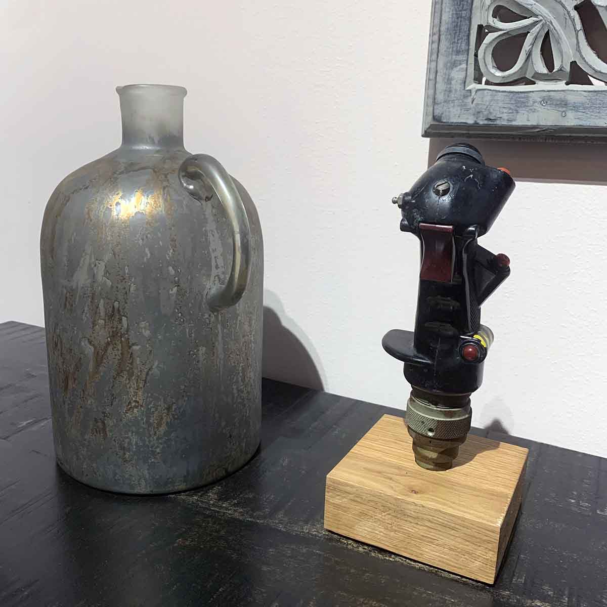 Original Belgian Air Force B-8 control stick grip next to a vase on a desk.