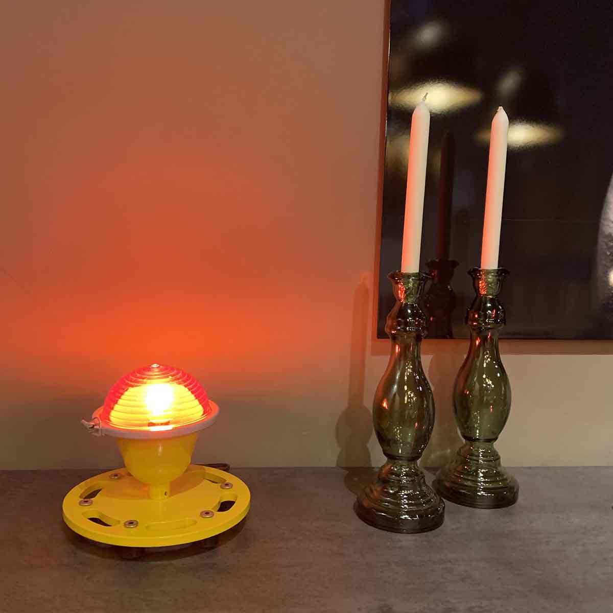 Refurbished World War II red runway obstruction light next to two candles.