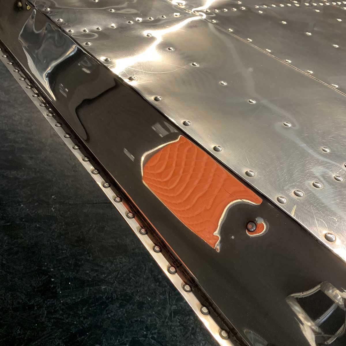 Detail showing the mirror polish on a Douglas DC-3 Dakota wingtip office desk.