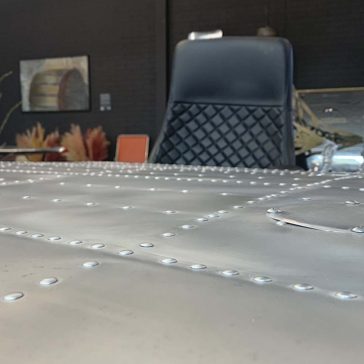 Office desk chair behind a Douglas DC-3 Dakota wingtip with matte finish and converted into a table.