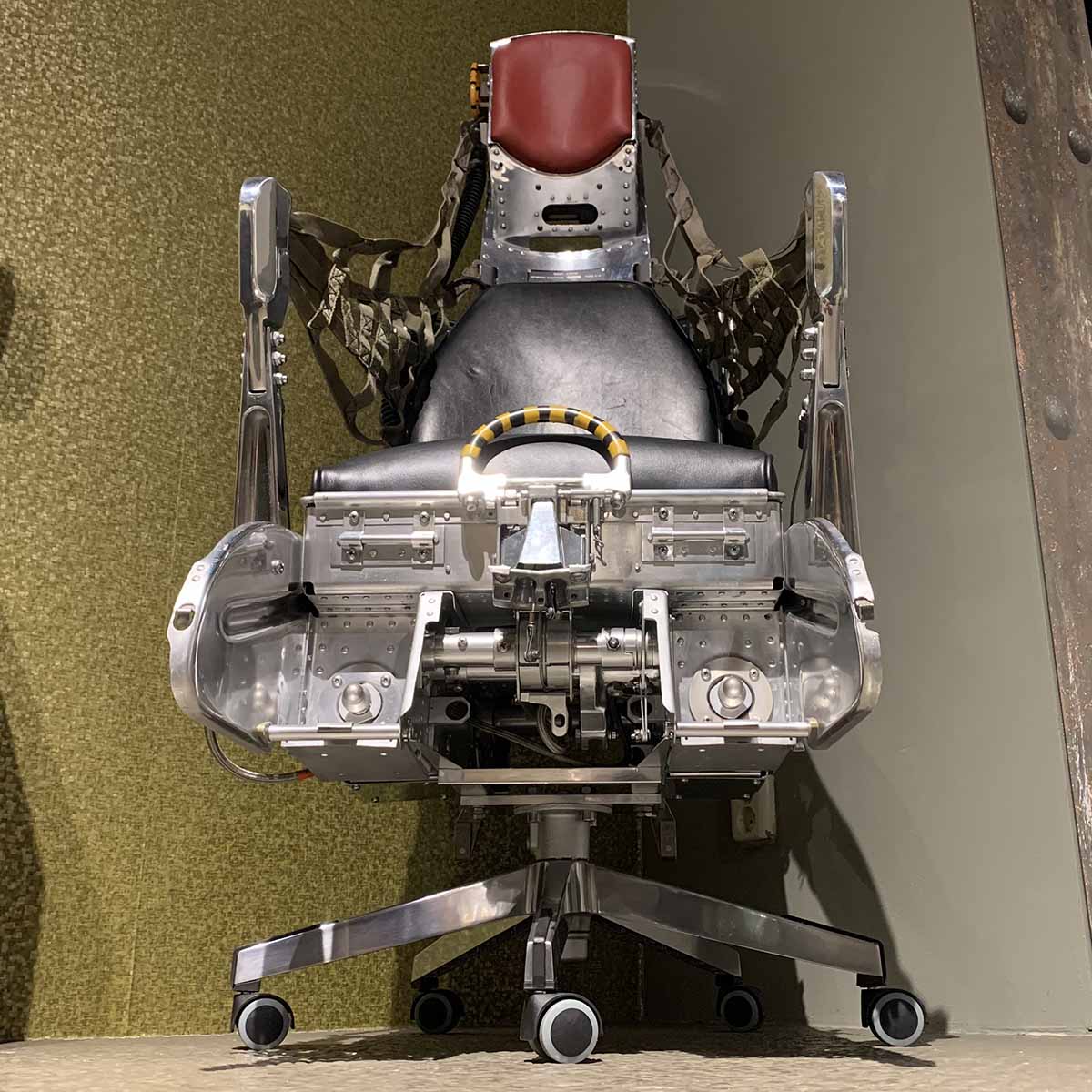 Office chair made of a polished Lockheed C2 ejection seat with arms in forward position.