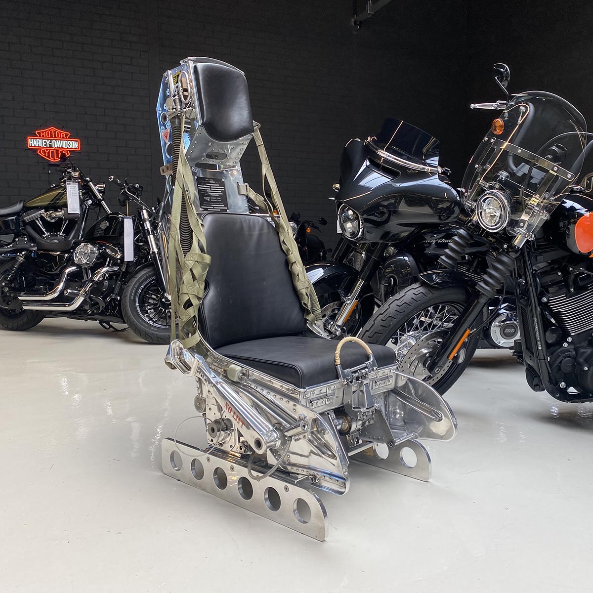 Mirror polished Lockheed C2 ejection seat from a Starfighter in front of a number of Harley-Davidson bikes.