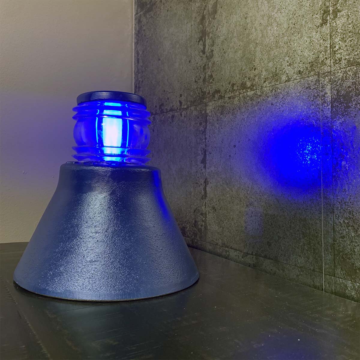 Refurbished Koninklijke Luchtmacht taxiway light with the blue light reflecting on the wall.