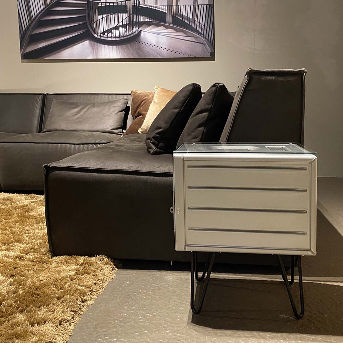 Upcycled aircraft galley container side table next to a dark brown couch.