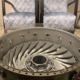 Living room table made of the gas generator case of a Pratt & Whitney Canada PW100 in front of two chairs.
