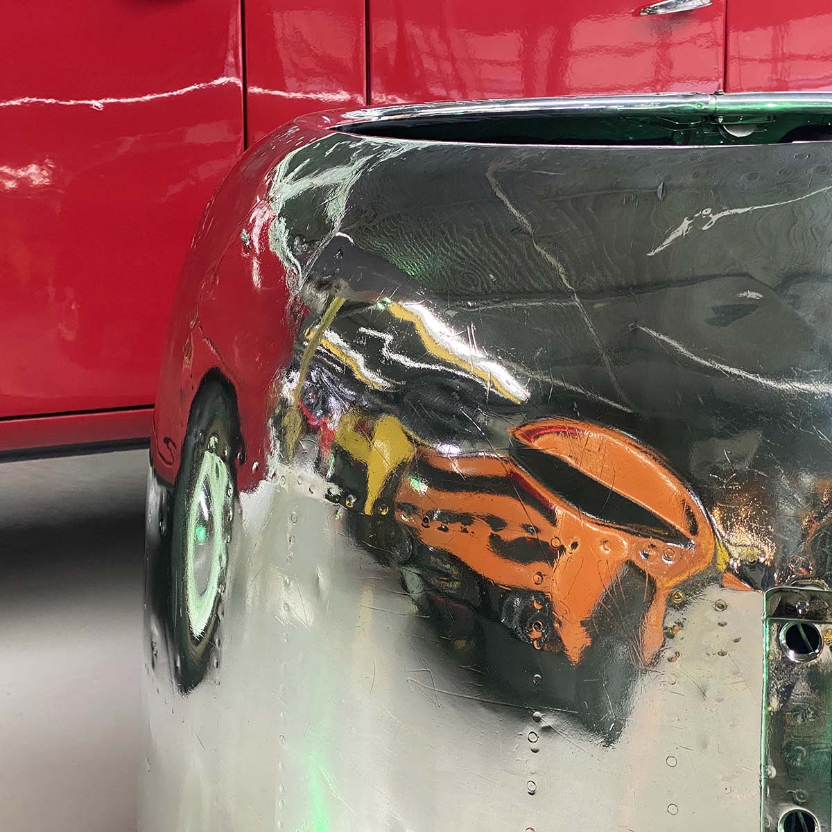 Reflection of super cars in a polished Douglas DC-3 Dakota engine cowling love seat.