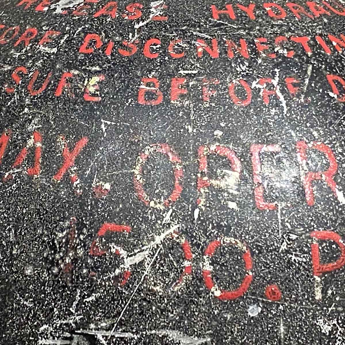 Detail of text on a hydraulic system accumulator from an aircraft.
