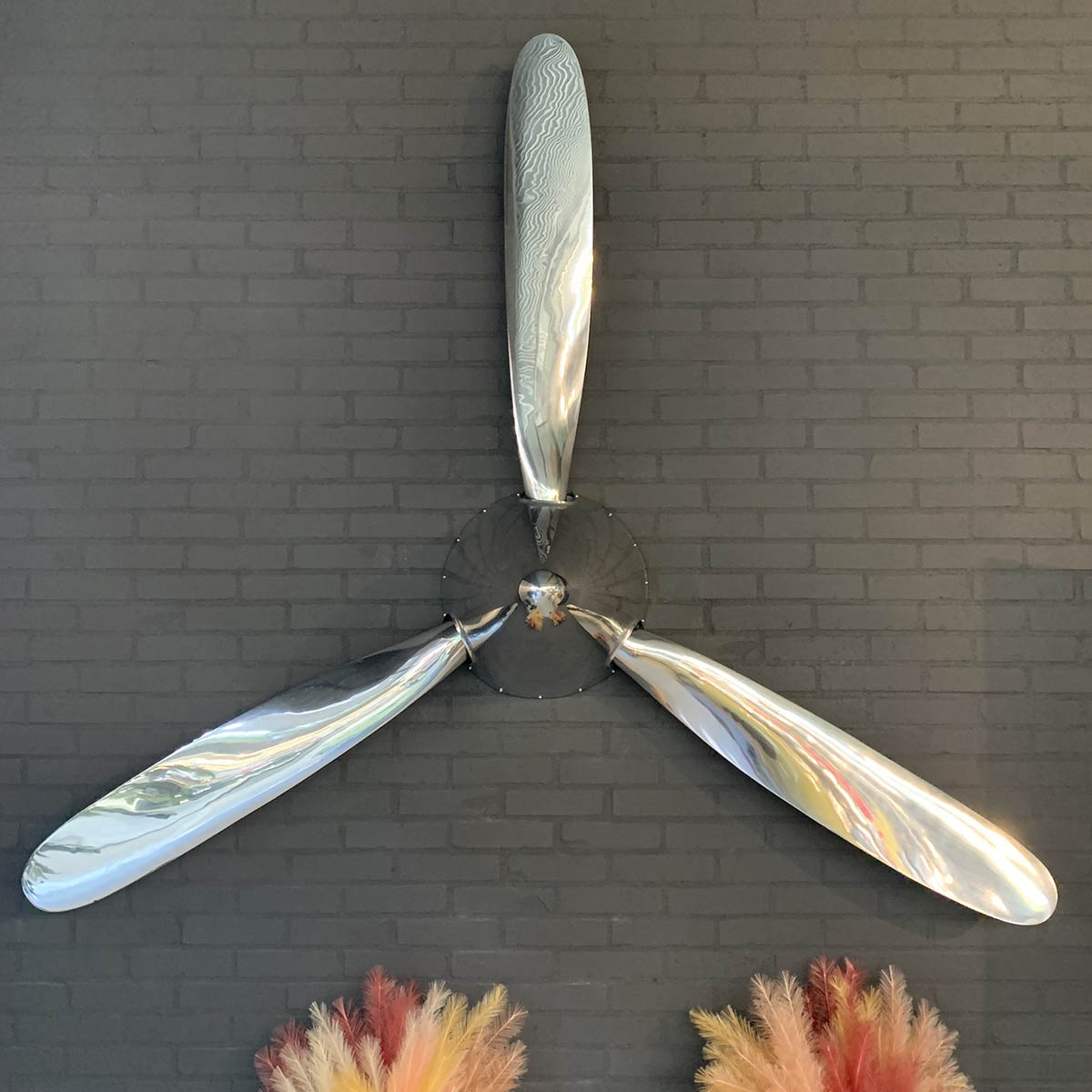 Polished Hartzell propellers and spinner hanging on a brick wall in Kaeve.