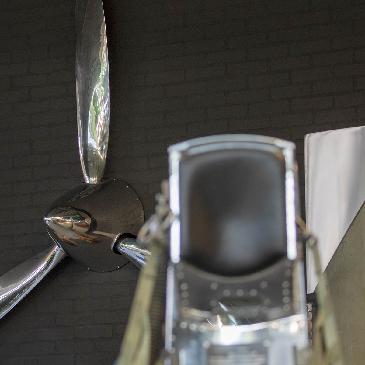 Polished three-bladed Hartzell propeller with spinner shown behind a Lockheed C2 ejection seat.