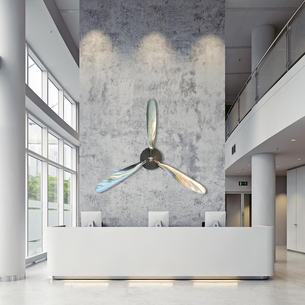 Polished three-bladed Hartzell propeller with spinner mounted on a wall in a modern business hall.