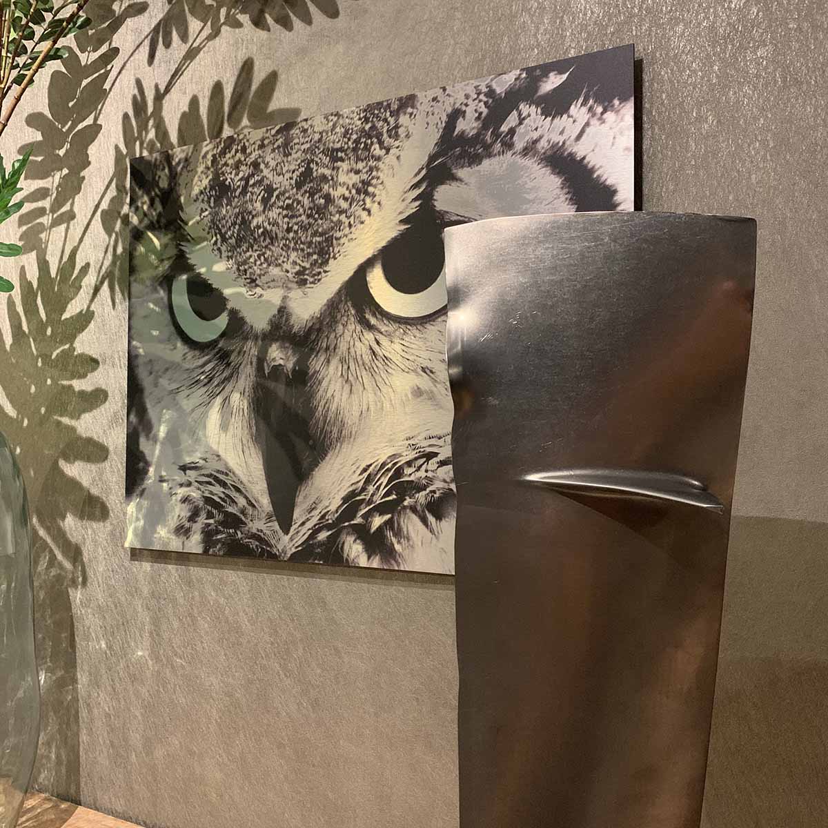 Top side of a Pratt & Whitney PW4000 engine fan blade in front of a photo of an owl.