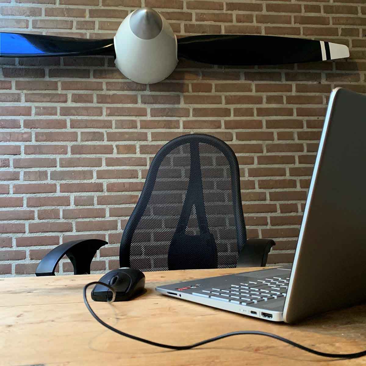 Two-bladed McCauley propeller in repainted colours, wall-mounted in an office setting.